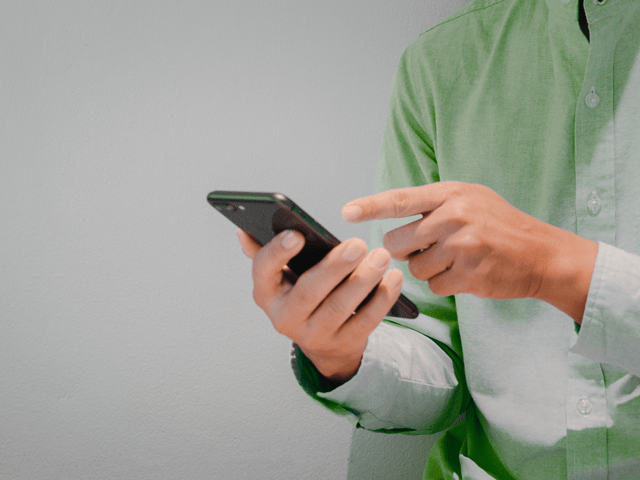 Bilde av en som holder mobiltelefon i handen